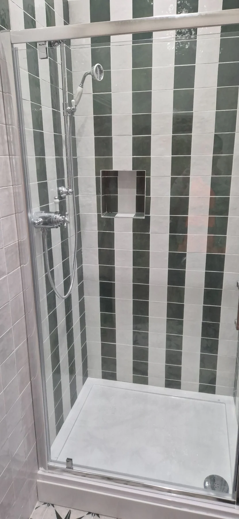 Completed striped charcoal and light tile shower with chrome fittings and glass screen